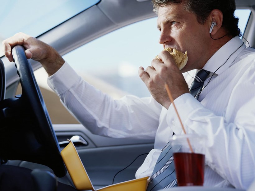 Mann isst während der Autofahrt